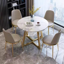 Charger l'image dans la galerie, Modern round marble dining table with gold base and four gray upholstered chairs, perfect for contemporary home dining spaces with elegant and stylish design.