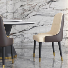 Charger l'image dans la galerie, A luxurious beige and brown upholstered dining chair with black legs and gold-capped feet, paired with a marble-topped dining table set against a marble wall backdrop. Frequently asked questions might include 'What are the best materials for an elegant dining chair?' and 'How do you choose chairs that complement a marble dining table?
