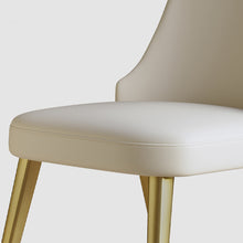 Charger l'image dans la galerie, Close-up of a sleek cream dining chair with gold metal legs, showcasing its soft cushion and modern design. Frequently asked questions include 'What is the most comfortable material for dining chair seats?' and 'How durable are gold metal legs on dining chairs?