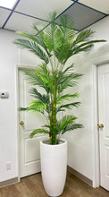 Charger l'image dans la galerie, A tall artificial palm tree displayed in a sleek white planter in a bright office space. The realistic-looking palm complements the minimalistic decor, positioned between two white doors with a thermostat on the wall to the left. The vibrant green leaves add a natural touch to the modern setting.