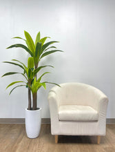 Load image into Gallery viewer, Artificial tall green plant with broad, vibrant leaves in a sleek white pot, paired with a modern cream armchair, perfect for contemporary home or office decor