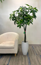 Charger l'image dans la galerie, Artificial money tree with lush green leaves in a stylish white textured planter, placed beside a cozy white armchair in a modern indoor setting, perfect for enhancing office or home decor