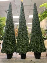 Charger l'image dans la galerie, Three tall, cone-shaped artificial topiary trees are displayed in black pots within an indoor setting, surrounded by other decorative plants. The uniform height and dense foliage of the trees create a visually appealing and symmetrical arrangement.