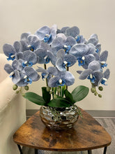 Load image into Gallery viewer, A stunning arrangement of artificial blue-speckled orchids in a metallic vase with glossy leaves. Frequently asked question: What are the best ways to clean artificial orchids without damaging their delicate appearance?