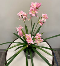 Charger l'image dans la galerie, A potted artificial plant featuring delicate pink flowers with long green leaves, placed on a white round table.