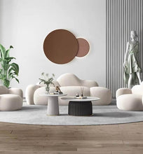 Charger l'image dans la galerie, What are the ideal coffee tables for a modern, minimalist living room? This chic space features a cloud-shaped sofa and matching armchairs paired with two round marble coffee tables with ribbed bases. The setup is enhanced by minimalist décor, including a large wall sculpture, indoor plants, and a statue, creating a sophisticated and contemporary design