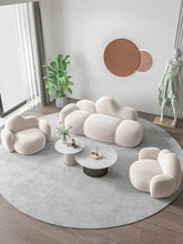 Charger l'image dans la galerie, How do I style coffee tables in a minimalist living room? This modern space features a plush cloud-shaped sofa and armchairs paired with two round marble coffee tables with ribbed bases. Decorative accents include a large wall art piece, indoor plant, and a statue, creating a balanced and elegant contemporary design with soft, neutral tones.