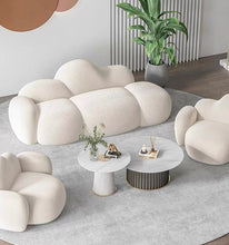 Charger l'image dans la galerie, What are the best coffee tables for a cloud couch setup? This modern living room features a plush white cloud-shaped sofa and armchairs paired with two round marble-topped coffee tables. The tables have sleek gold accents and complement the soft, inviting furniture, creating a cozy and stylish atmosphere. A large plant and minimal décor enhance the contemporary design.