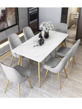 Charger l'image dans la galerie, What are the best dining table sets for a modern kitchen? This sleek dining room setup features a white marble table with gold legs, surrounded by six gray velvet chairs, also with gold legs. The minimalist design creates a luxurious and contemporary feel, perfect for modern interiors.