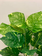 Charger l'image dans la galerie, Close-up of artificial plant leaves showing vibrant green tones with yellow variegation, creating a lush, tropical look. The leaves appear glossy and healthy, giving the plant a realistic appearance.