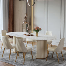 Load image into Gallery viewer, Luxurious round marble-top dining table with golden legs, paired with plush cream-upholstered chairs featuring vertical channel tufting and gold-toned legs, set on a soft gray rug in an elegant, light-filled room.