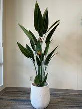 Charger l'image dans la galerie, White planter with a crater-like textured design, holding an artificial bird of paradise plant with vibrant green leaves and orange flowers, placed indoors on a carpeted floor. Is this planter suitable for large indoor plants?