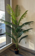 Charger l'image dans la galerie, Artificial palm tree in a black pot by a window, with lush green fronds creating natural shadows, perfect for home or office decor.