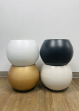 Load image into Gallery viewer, Four spherical planters in different finishes—white, black, gold, and cream—stacked in pairs, placed on a wooden floor against a plain wall.