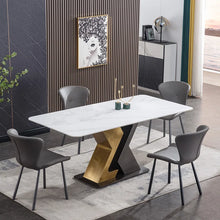 Charger l'image dans la galerie, Modern rectangular white marble dining table with black and gold geometric base, surrounded by gray upholstered chairs in a stylish dining area with wood accent wall