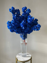 Load image into Gallery viewer, Vibrant blue artificial flowers elegantly arranged in a tall, clear glass vase filled with water, showcased on a chic marble and gold pedestal. Ideal for weddings, events, and upscale décor. How can these striking blue blooms transform your event?