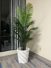 Charger l'image dans la galerie, A vibrant green indoor plant displayed in a tall, white, spiral-patterned planter placed near a window with vertical blinds, set on a modern carpeted floor.