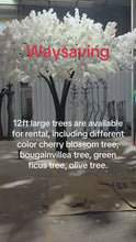 Load and play video in Gallery viewer, Artificial tree with lush white blossoms and a realistic trunk, displayed in a workshop setting, ready for rental as stunning decor for weddings and events. Are these trees easy to assemble and transport for venue setup?
