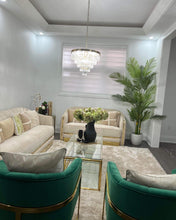 Charger l'image dans la galerie, A chic living room with neutral furniture, gold accents, a faux palm tree, and a crystal chandelier for a modern, elegant look.