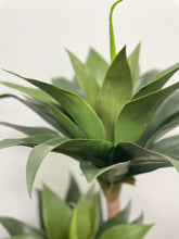 Charger l'image dans la galerie, Close-up shot of the base of an artificial yucca plant, featuring realistic green leaves and a textured faux trunk, showcasing the intricate detail for indoor home or office decor.