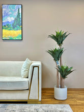 Charger l'image dans la galerie, Modern living room setup featuring a cream-colored sofa with a faux yucca agave plant in a white pot next to it. The artificial plant adds greenery to the minimalist decor, enhancing the stylish interior design.