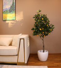 Load image into Gallery viewer, Artificial lemon tree with realistic green leaves and vibrant yellow lemons, placed in a black planter beside a white armchair, perfect for adding a touch of nature to indoor spaces.