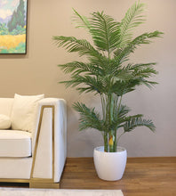Charger l'image dans la galerie, Artificial palm tree with green fronds, placed in a sleek white pot next to a white sofa, adding a natural touch to a modern, well-lit living room.