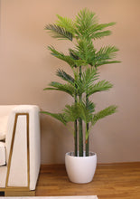 Charger l'image dans la galerie, Modern living room featuring a stylish white sofa with gold accents, a vibrant green palm tree in a white planter, and a colorful framed artwork on the wall.