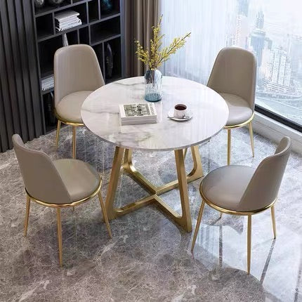 Elegant Round Dining Table with Glossy Sintered Stone Top and Gold Metal Legs, Surrounded by Four Grey Upholstered Chairs in Modern Apartment Setting with Marble Flooring
