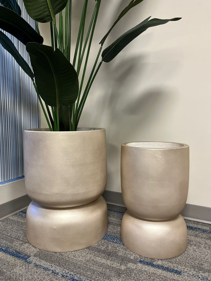 Gold planters with a smooth metallic finish, displayed empty indoors on a carpeted floor near a window. Is this planter suitable for modern minimalist decor?