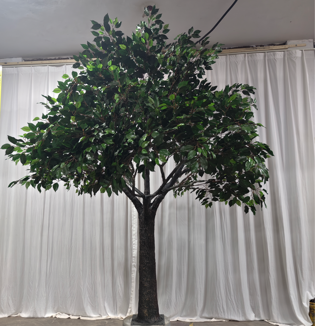 Realistic artificial green tree against a white draped backdrop, ideal for creating a nature-inspired ambiance at weddings and events. How easy is it to set up this artificial tree for indoor events?