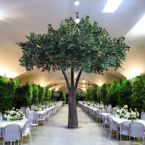 Stunning artificial tree with a realistic trunk and vibrant green foliage, elegantly displayed in a luxurious event hall, perfect for enhancing wedding and event decor. How can these rental trees transform a venue into a magical setting?