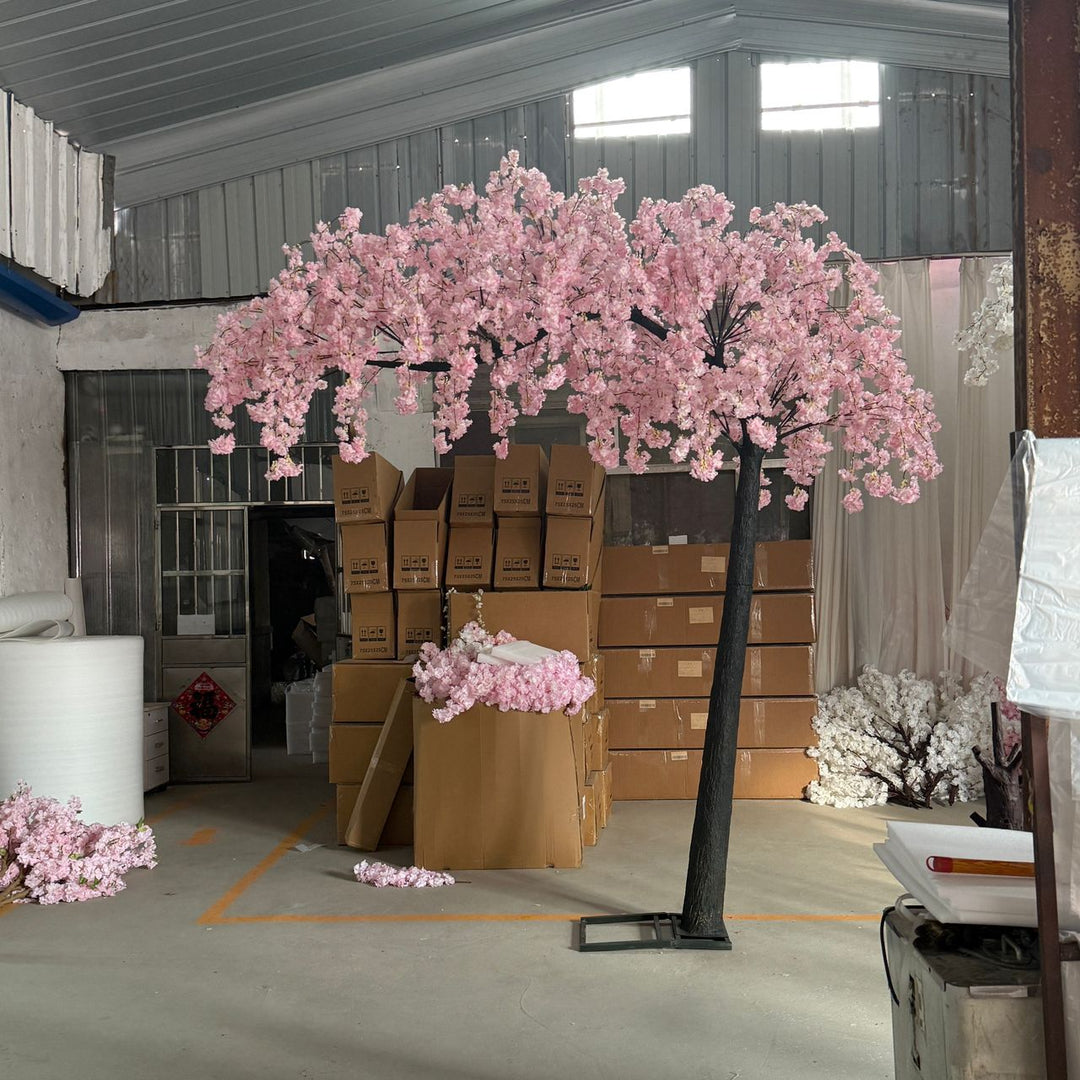Artificial arch pink weeping cherry blossom tree with pink flowers in a warehouse setting.
