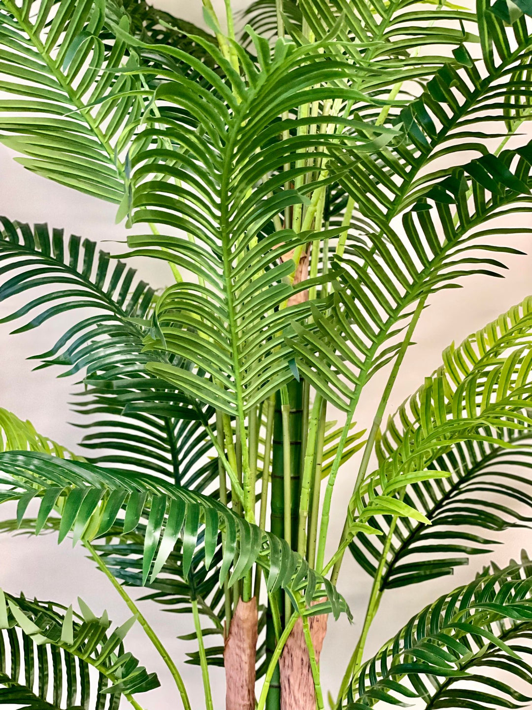 Close-up of vibrant green artificial palm leaves, showcasing their detailed texture and lush tropical aesthetics.