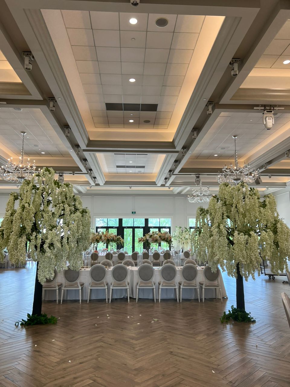 Decorated event space with white wistera floral arrangements and tables.