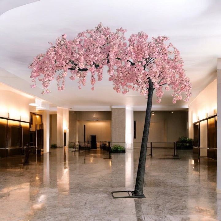 Artificial  pink weeping cherry blossom  arch tree in a large indoor space with marble floor.
