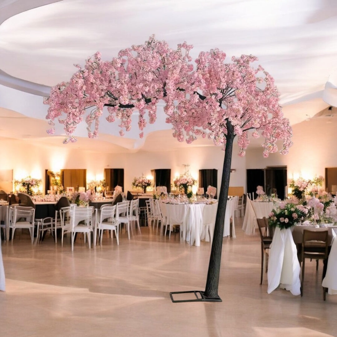 Decorative pink weeping cherry blossom  arch tree in a large room with tables and chairs.