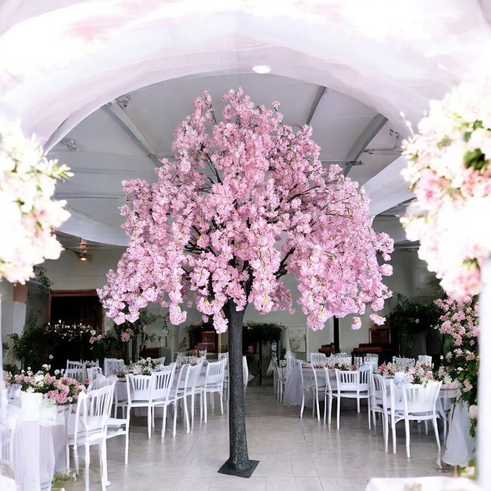 Decorative pink weeping cherry blossom flowering tree in a wedding reception setting with white chairs and tables.