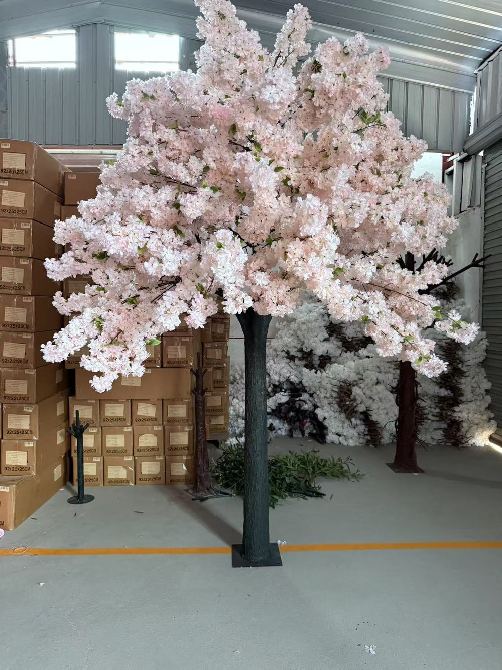 Artificial white pink cherry blossom tree in a warehouse setting.