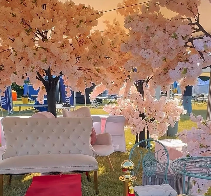 Decorative outdoor setting with white pink cherry blossom tree , white furniture, and a gold trophy in Toronto.