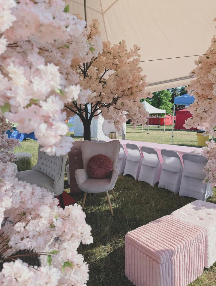 Outdoor setting with white pink cherry blossom tree , chairs, and a striped ottoman under a canopy in Toronto.