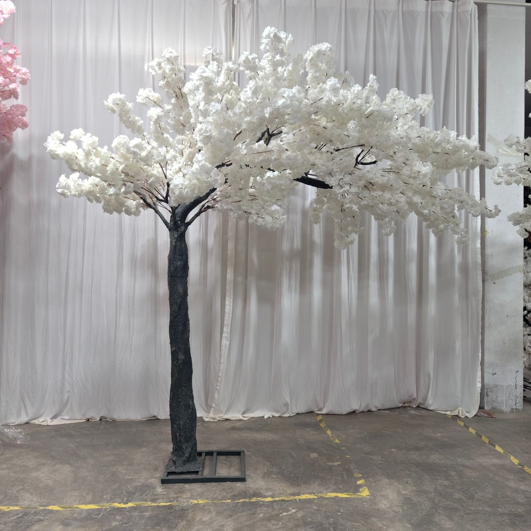 Faux white cherry blossom arch used in front of white drapey backdrop at an event.