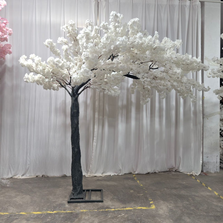 Faux white cherry blossom arch used in front of white drapey backdrop at an event.