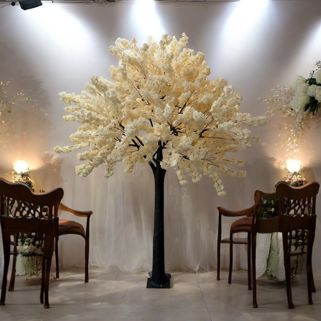 Decorative white tree with lights in a room with chairs and lamps.