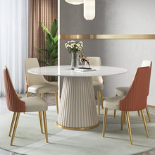 Charger l&#39;image dans la galerie, Elegant dining room with a modern round table featuring a fluted base and marble top, complemented by five stylish chairs with beige and orange upholstery and gold legs, set against a chic gray and gold-accented wall with a touch of greenery.

