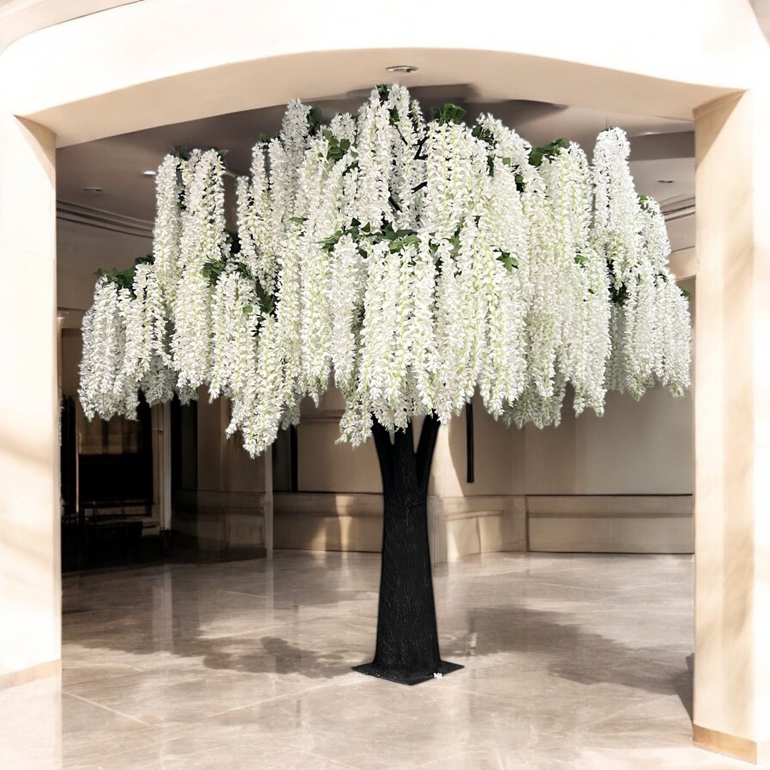 Artificial white wisteria tree in a large indoor setting with marble floor and beige walls.