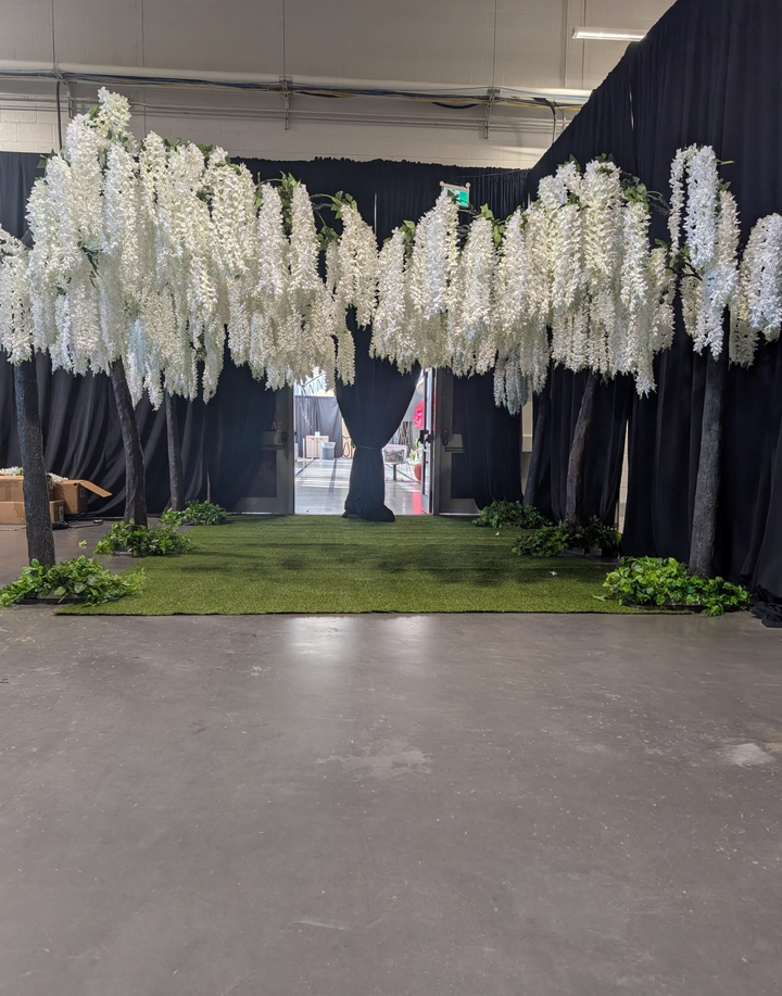 Close-up of white wisteria blooms hanging from a tall artificial arch tree at CNE Toronto.