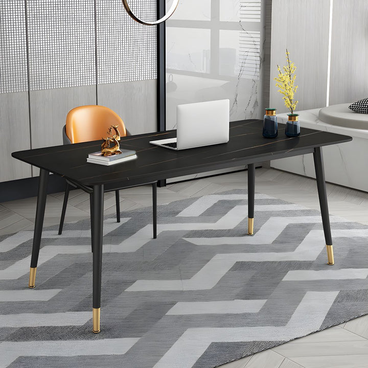 What is the best modern desk for a stylish home office? This sleek black desk with gold-accented legs offers a minimalist workspace, paired with a contemporary orange chair. The clean design is complemented by decor accents and a geometric rug, creating a functional and modern home office setup.