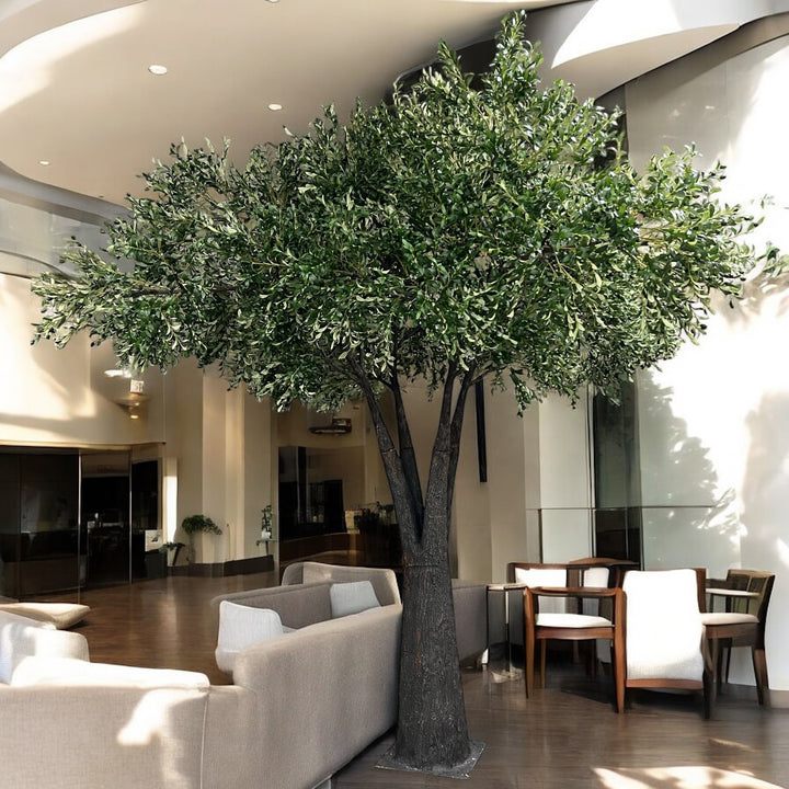 Large artificial olive tree in a modern indoor setting with furniture and decor.