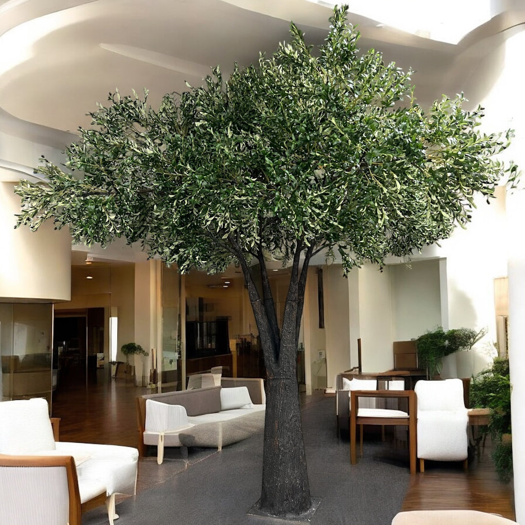 Large artificial olive tree in a modern indoor setting with furniture and decor.